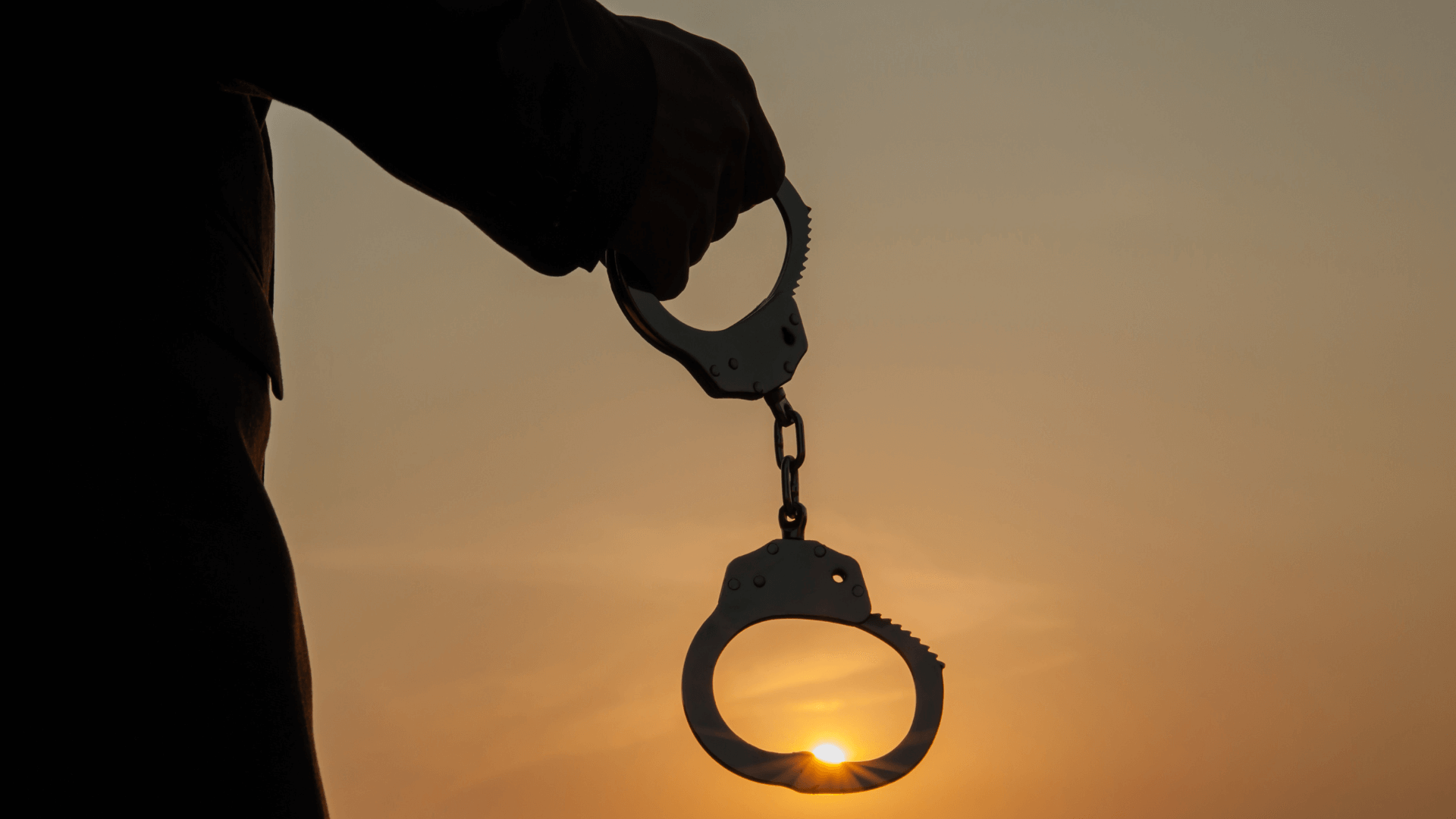 Silhouette of an open handcuff against a sunset sky, symbolizing freedom, rehabilitation, and the transformative power of music therapy in forensic settings